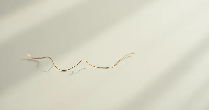 Single thread being untangled on a plain pale surface (illustration)