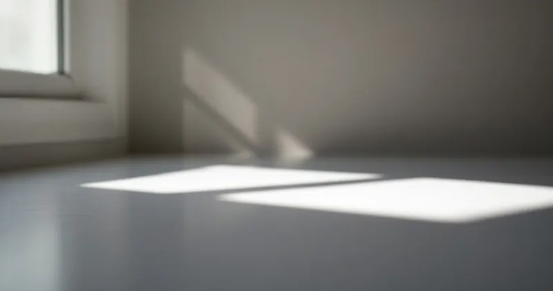 Soft geometric window light falling across a plain desk surface (illustration)