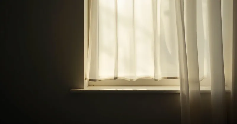 Soft light through sheer curtains onto a plain windowsill (illustration)