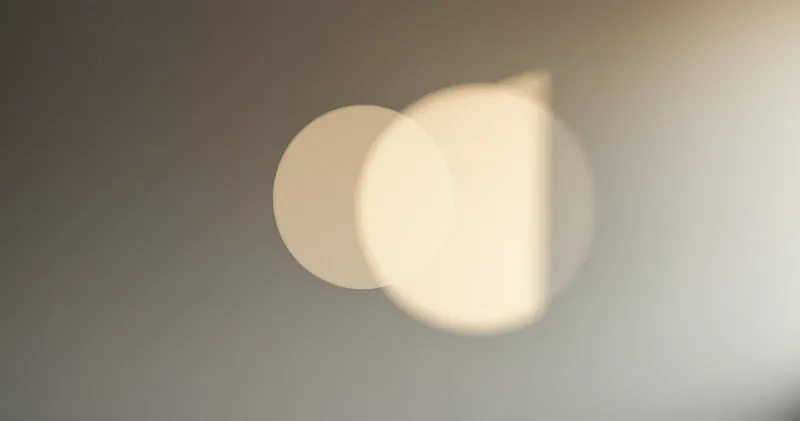 Two overlapping circles of soft light on a plain wall (illustration)