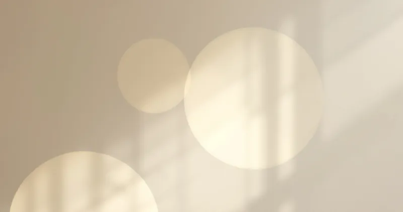 Two soft circles of light overlapping on a pale wall (illustration)