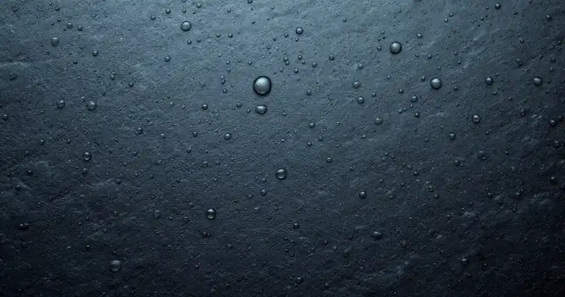 Rain drops beaded on a dark slate surface (illustration)